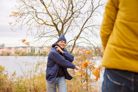 Happy young man throwing autumn leaves