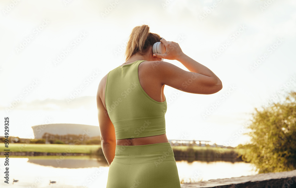 Sticker Rearview of a sports woman listening to music on headphones outdoors