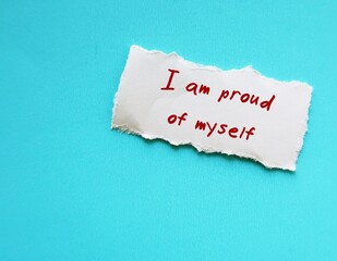 on blue copy space background, torn paper with handwriting  I AM PROUD OF MYSELF, positive  mantra...