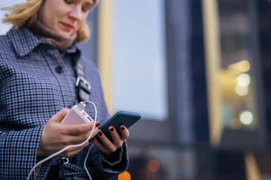 Young woman using phone and power bank outdoors