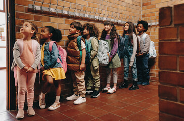 Primary school students waiting in line outside their classroom. Children waiting to start class in...