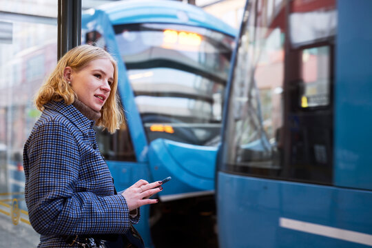 Woman using cell phone at tram stop
