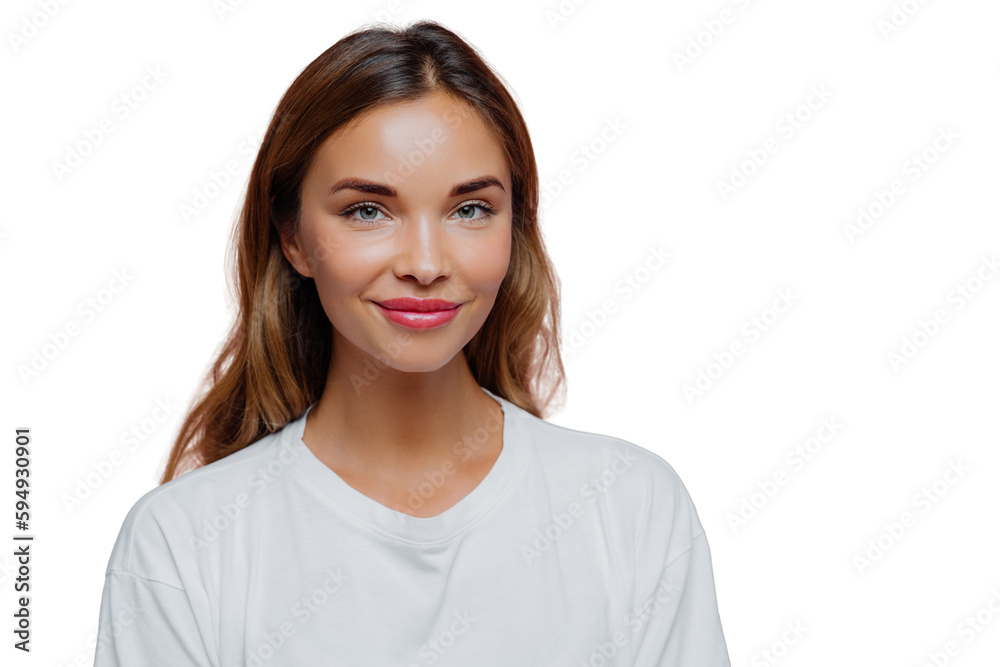 Wall mural Pretty young woman uses cosmetics for looking young and beautiful, has long hair, looks confidently at camera with happy tender smile, wears casual outfit, poses over purple wall, blank space on right