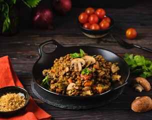 Green lentil stew with vegetables and mushrooms on a black plate on a dark wooden background. Vegan recipes, lenten menu, healthy food, diet.