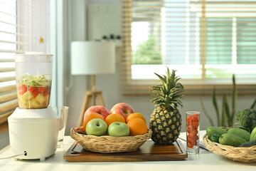 Blender with fresh vegetables and fruits on table in kitchen. Healthy drink and vegetarian food concept