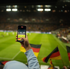Mann macht mit Smartphone ein Foto bei einem Deutschland-Spiel im Stadion - 594937705