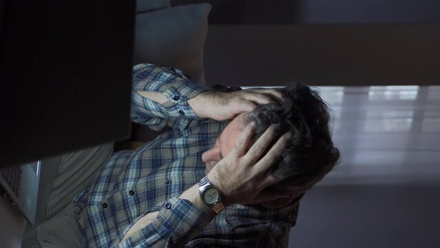Vertical Video of Man working from home looking at laptop and seeing something bothering him and getting upset.