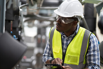 Male plumber engineer inspecting quality of work at sewer pipes area at construction site. African American male engineer worker check or maintenance sewer pipe network system at rooftop of building