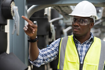 Fototapeta na wymiar Male plumber engineer inspecting quality of work at sewer pipes area at construction site. African American male engineer worker check or maintenance sewer pipe network system at rooftop of building