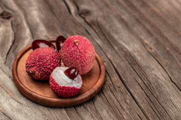 Ripe lychee. Exotic asian fruits in bowl on plate on a wooden background, Long banner format. top view