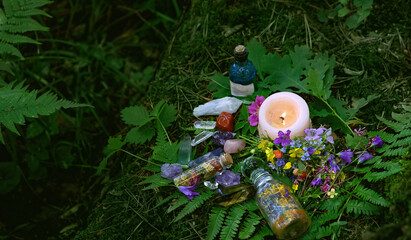Candle, witch bottles, crystals and flowers on dark forest natural background. Witchcraft, magic spiritual practice. pagan, Wiccan, Slavic traditions. esoteric ritual for Midsummer, Litha sabbath