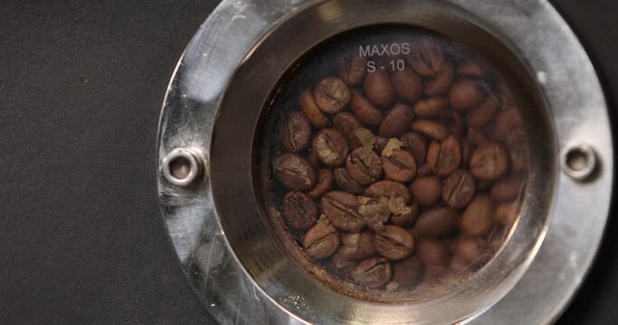 Window of an industrial coffee roasting machine with coffee beans inside. Close-up. Modern equipment. Industrial cooking arabica and robusta.