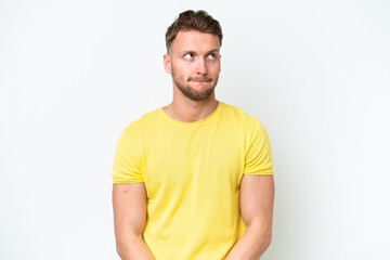 Obraz premium Young blonde caucasian man isolated on white background having doubts while looking up
