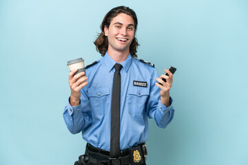 Young police caucasian man isolated on blue background holding coffee to take away and a mobile