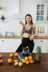 Young attractive woman eat fruits on table in kitchen at home. Beautiful active female stand with happy face, enjoy eating apple, healthy foods for health care wellness to lose weight in house