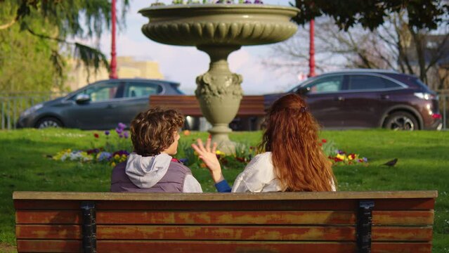 Caring mother talking to her son outdoor. A teenager discusses with his mom on a bench in the park. Raising a child by a mother, a serious conversation with a teenager in adolescence