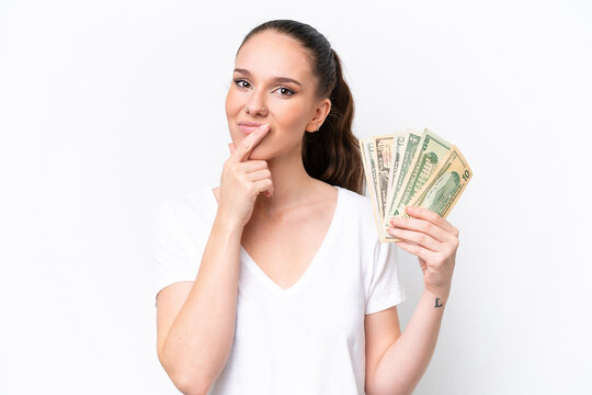 Young caucasian woman taking a lot of money isolated on white background thinking