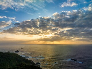 Obraz premium Magnificent sunset overlooking the dramatic cliffs and lush green grass of the coast, Pacific Ocean