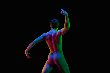 Portrait of one young attractive dancer, actor with naked torm posing over dark studio background...