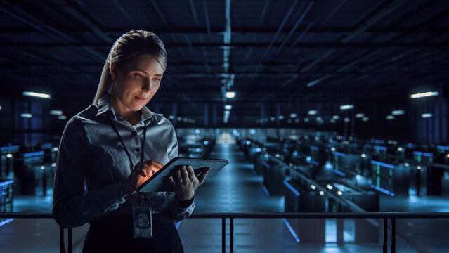 Successful Data Center IT Specialist Using Tablet Computer. Server Farm Cloud Computing Facility with Female System Administrator Working. Data Protection Engineering for Cyber Security.