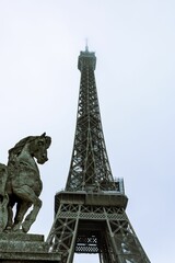 the horse statue is on top of the ledge in front of the eiffel