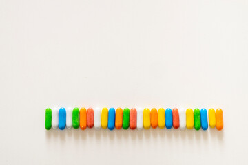 Delicious colored sweet licorice candies in capsules or pills on a white background, forming a horizontal line, with space for text, copy space