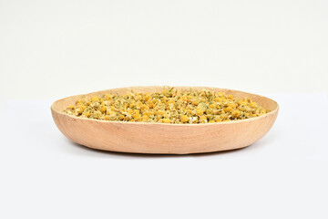 Chamomile flowers on a plate. top view. dried chamomile on white background. Chamomile tea ingredient.	