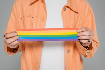 Cropped view of gay man holding lgbt flag isolated on grey.