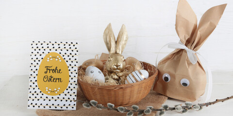 Karte Frohe Ostern mit goldenem Osterhasen in einem Osternest als Geschenk - 594963370