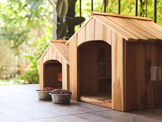 two empty wooden dog's houses with dog food bowls  in balcony decorated with houseplant in plant...
