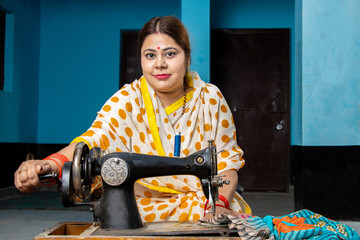 Portrait happy traditional indian woman housewife wearing sari using sewing machine at home. Skill india Concept.