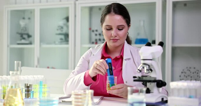 A young woman in the laboratory uses PH Meter, a close -up. Diagnosis of urine analysis, slowmotion