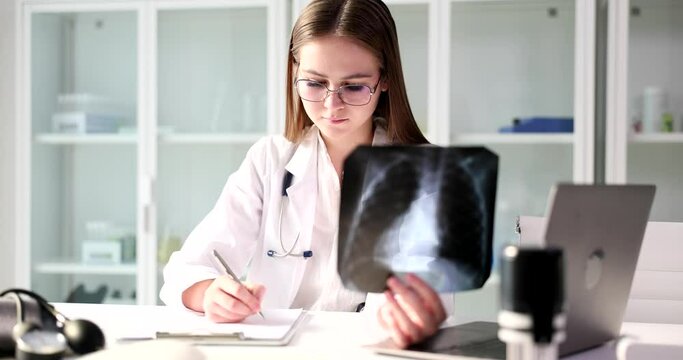 The young doctor holds an X -ray and writes a close-up. Diagnosis of the disease and injury, fluorography