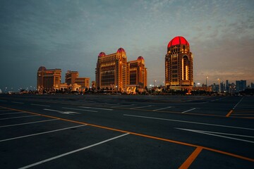 an empty parking lot with buildings in the background at sunset