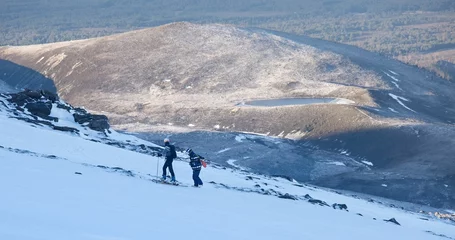 Fotobehang two people with skis walking up a hill in the snow © Somewheresky/Wirestock Creators