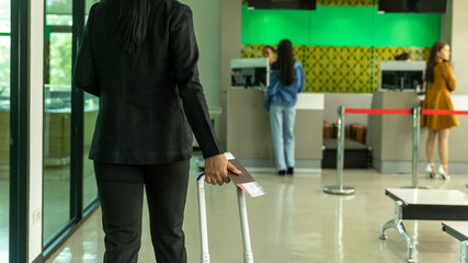 Female business traveler caries a blue small suitcase to check in counter before taking flight at an airport. Lady walks with her carry on bag to the gate getting her journey.