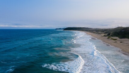 Fototapeta na wymiar Ocean shoreline with rolling waves lapping against the sandy beach.