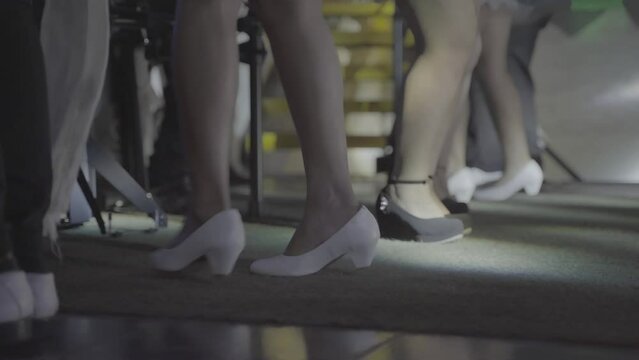 A closeup shot of dancing feet on the stage. They're wearing white and black shoes while tap dancing.