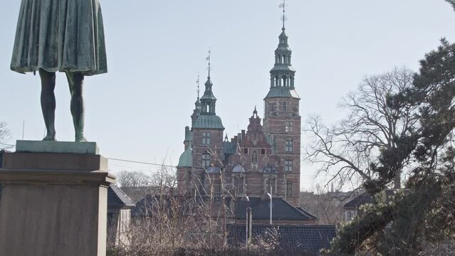 Statue with the Rosenborg Castle in the background in Copenhagen, Denmark against the blue sky