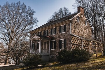 Old stone house, nestled on a grassy hillside, surrounded by a canopy of trees