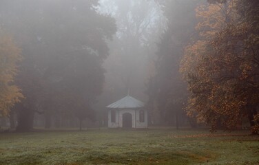 the foggy park has a small white building in it