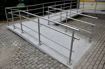 Fotobehang the curved ramp at the entrance to the building is suitable for wheelchair access and supply to the building. stainless steel railing, concrete surface © Michal