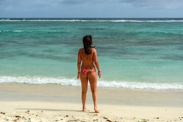 Young female adult standing on a beach, wearing a colorful bikini