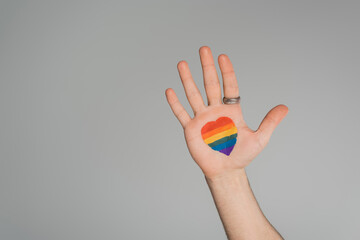 Cropped view of gay man with lgbt flag in heart shape on hand isolated on grey, International day...