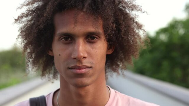 handsome young hispanic guy curly hair portrait student, backpacker traveler, looking at camera