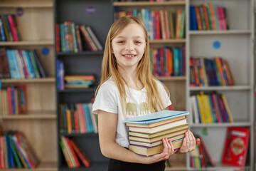 Child buys books in bookstore for learning or reading. Girl choosing book in school library.