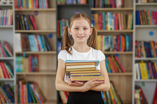 Child buys books in bookstore for learning or reading. Girl choosing book in school library.