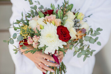 A beautiful wedding bouquet of flowers in the hands of the bride. Morning at the hotel. Close-up of hands with flowers. Wedding.