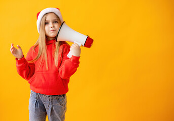 Portrait of a child girl in a Santa hat screaming into a megaphone, color background