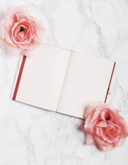 Open notebook decorated with roses isolated on white marble background. Flat lay. Top view. Copy space.